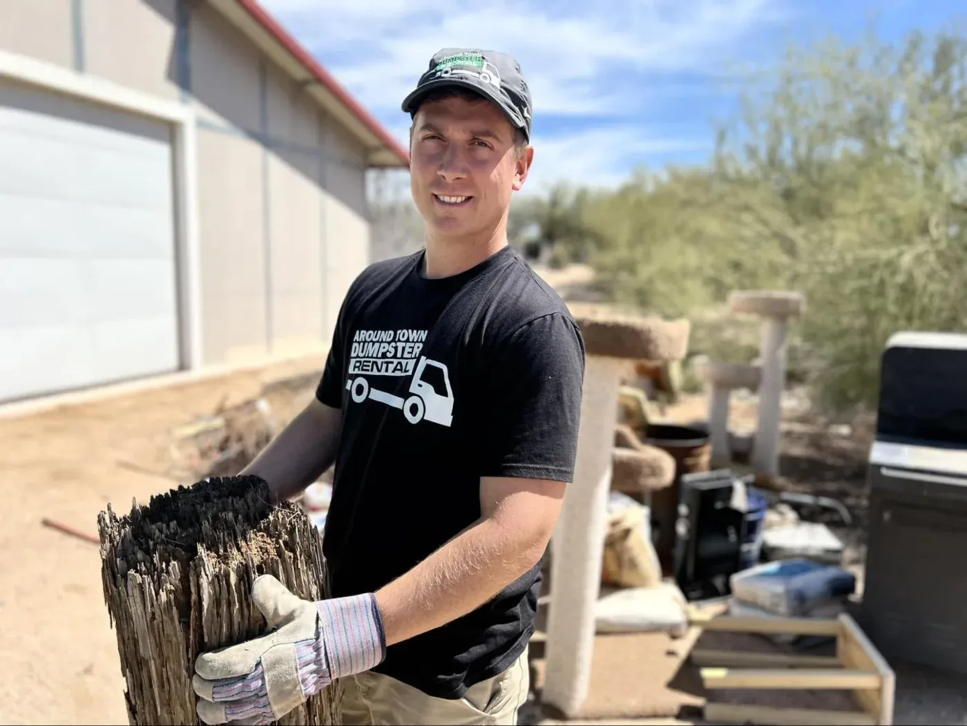 A crew member carrying a weathered wooden fence panel from a Black Canyon City property