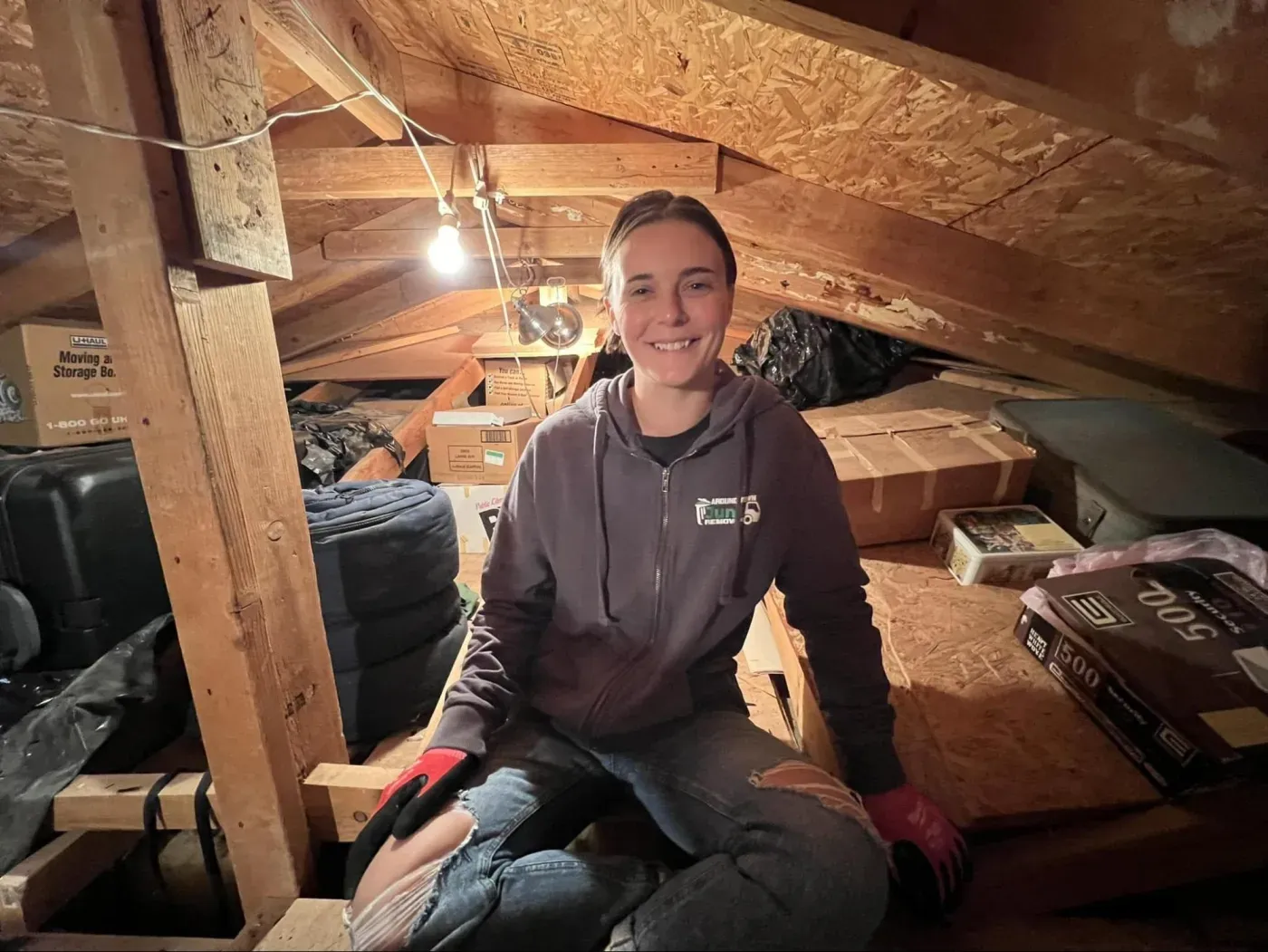 A crew member inside a Sun City attic surrounded by decades of stored boxes and belongings
